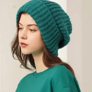 Frau mit grob gestrickter Beanie im Profil vor hellem Hintergrund