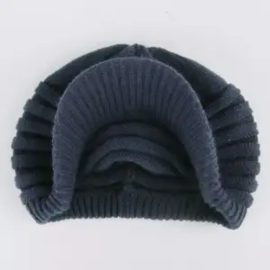Dunkelblaue Strickmütze mit Schirm und Rippenstruktur, flach auf hellem Hintergrund fotografiert