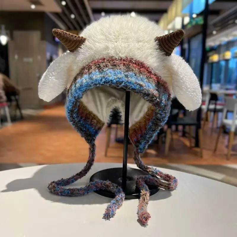 Plüschmütze mit braunen Hörnchen, Ohrenklappen und buntem Strickrand auf einem Ständer